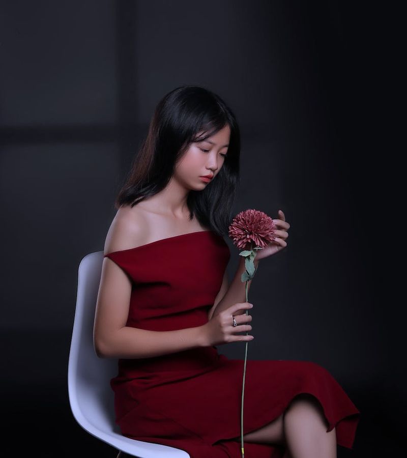 Woman holding a serene yoga pose in a dark, minimalist studio.